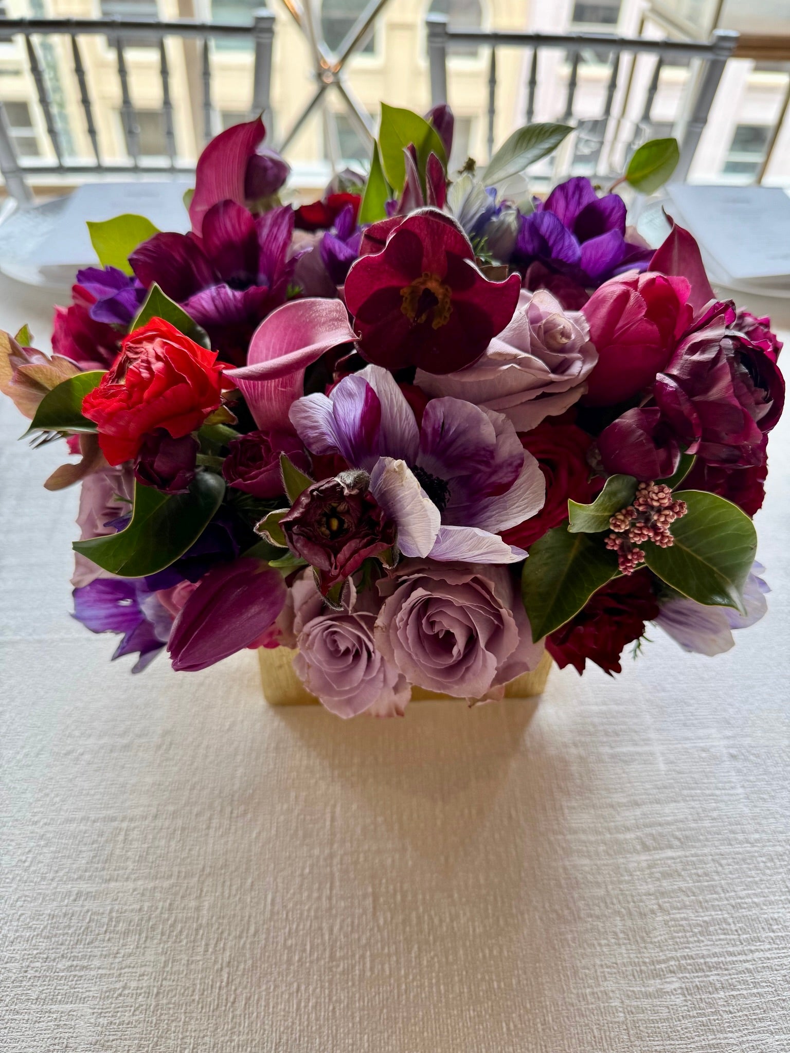 compact seasonal centerpiece of roses, ranunculus, anemone, calla, hellebore, calla lily and sumac