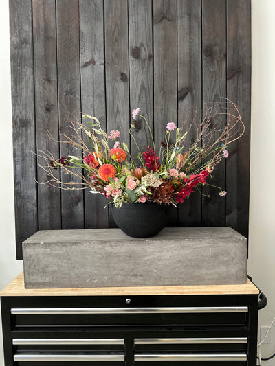 a fun design floral arrangment of dahlias and roses and other yummy thing sin a modern black pot by acme floral co