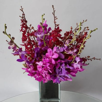 this flower arrangement is done in clear glass vase and packed full of colorful orchids for a luxurious gift